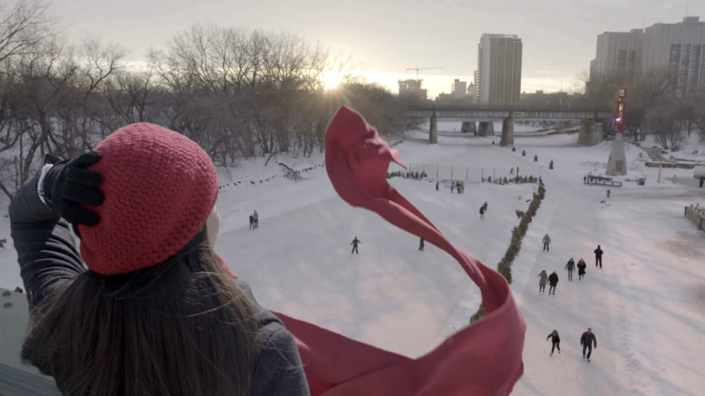 a woman with flowing scarf overlooks winnipeg's river skating trail